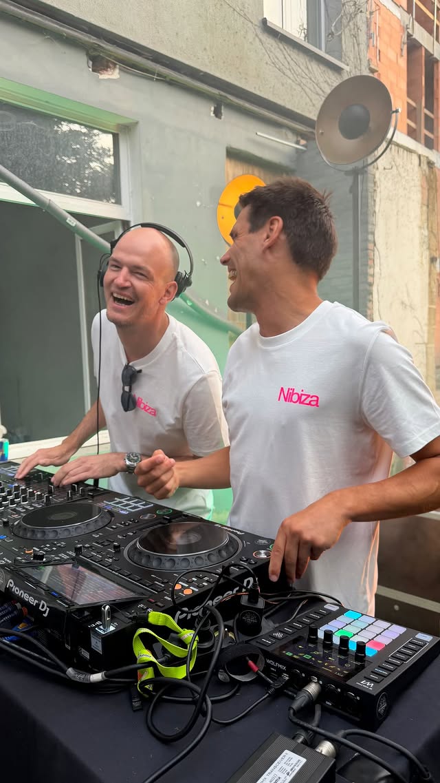 Twee dj's die het samen uitlachen achter de draaitafels.