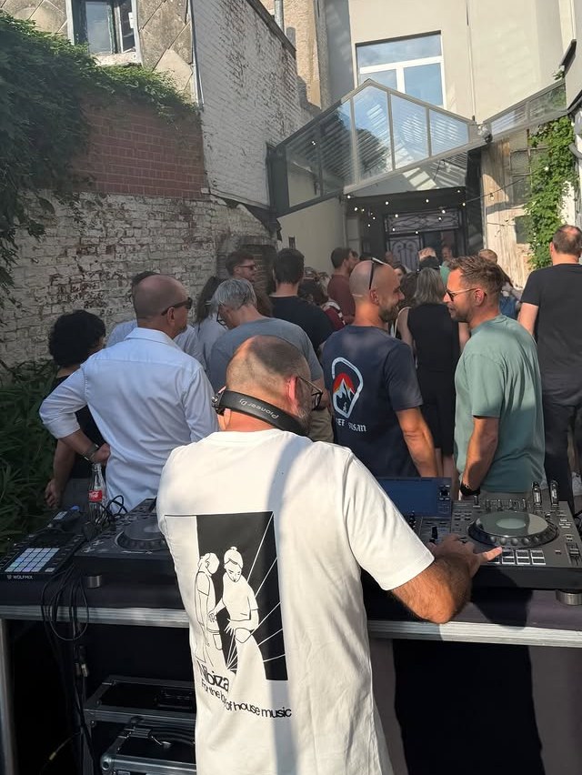 Over de schouder van de dj: de volle koer onder een blauwe hemel.