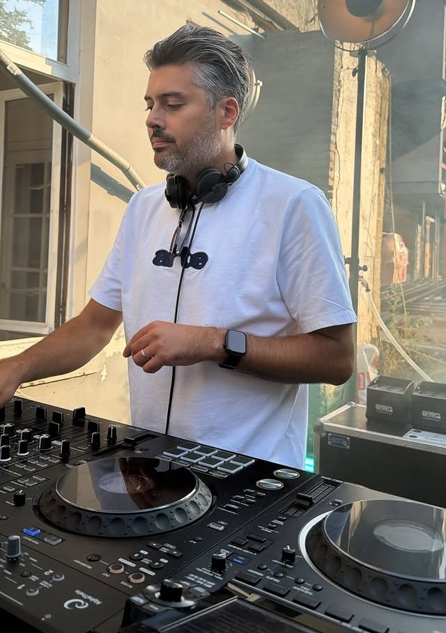 Een gast-dj achter de decks terwijl de zon lager komt te staan.